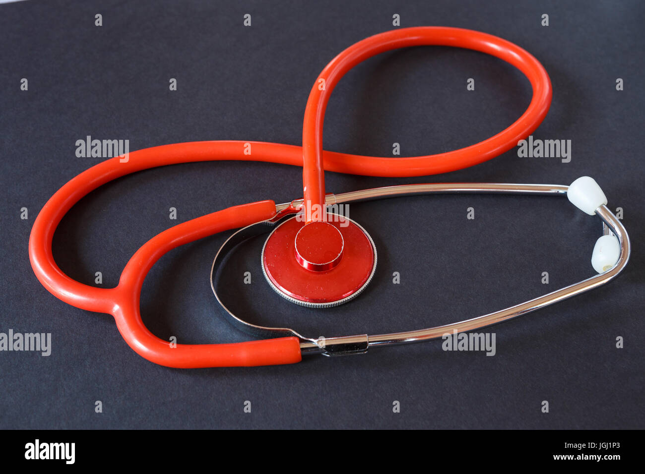 Rosso stetoscopio medico su sfondo nero. Strumento medicale per l'ascolto. Foto Stock
