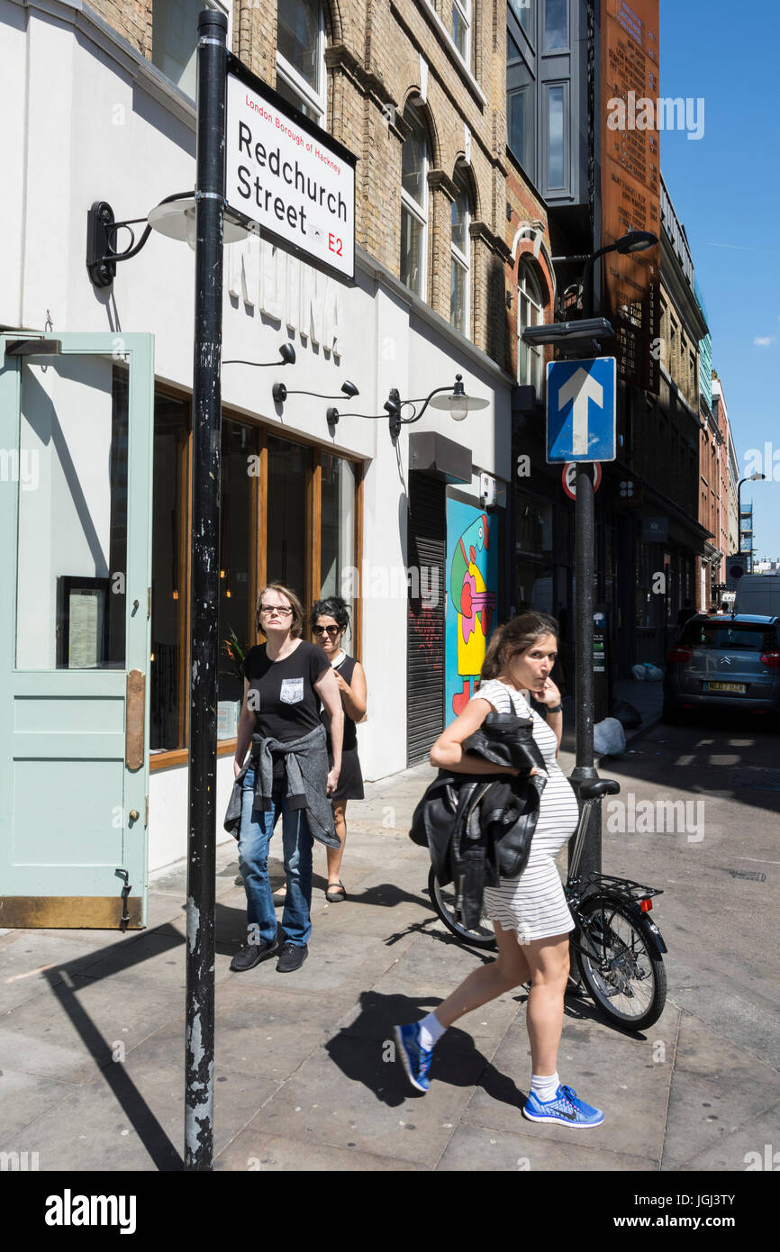 Una donna incinta che cammina vicino a Redchurch Street, Shoreditch, Londra, E2, Regno Unito Foto Stock
