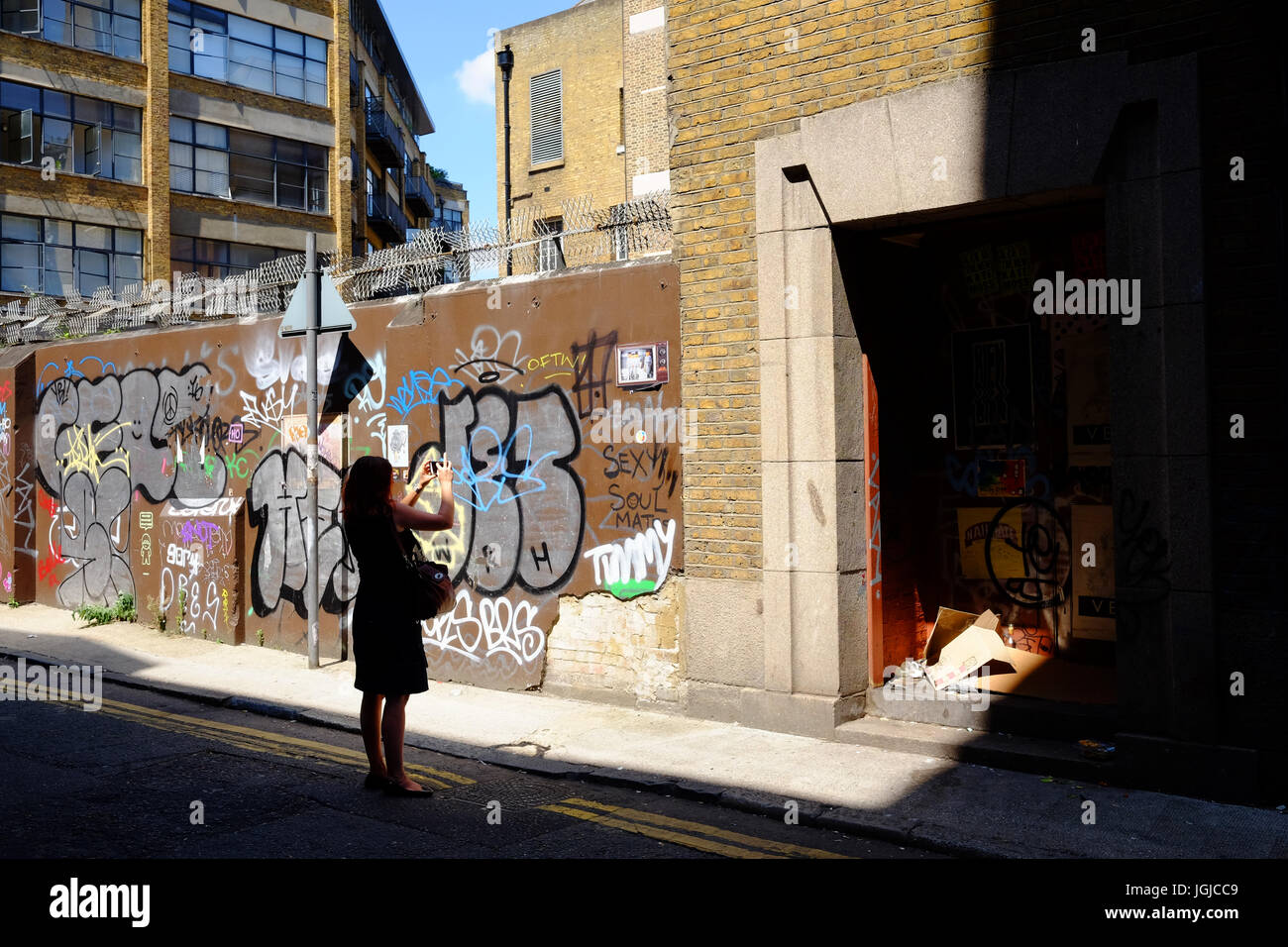 Persona prendendo fotografie dei graffiti in Corbet posto vicino a Brick Lane, Shoreditch, London E1, utilizzando il suo smartphone Foto Stock