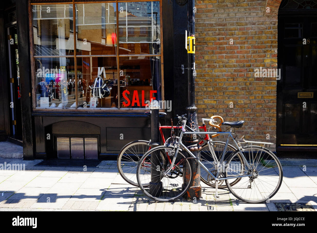 Biciclette parcheggiate fuori un negozio nel documento Wilkes Street in Shoreditch, nell'East End di Londra. Il negozio ha una vendita a. Foto Stock