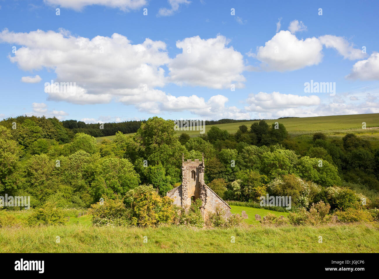 Una vecchia chiesa in rovina a wharram percy village nel yorkshire wolds circondata da una pittoresca campagna sotto un cielo di estate blu Foto Stock