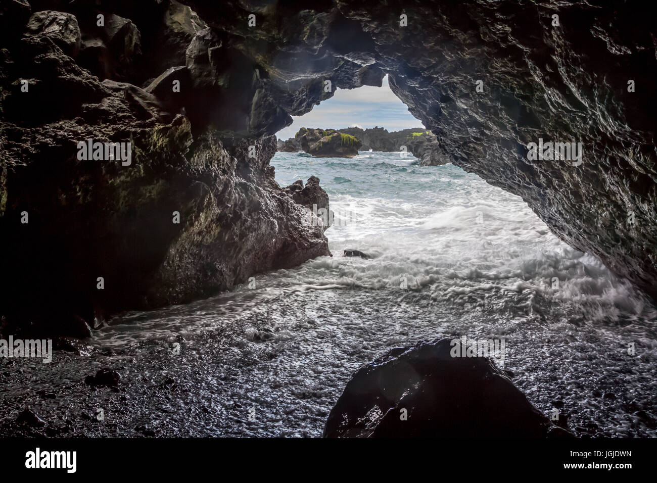 La laminazione delle onde in una grotta a Waianapanapa spiaggia di sabbia nera vicino a Hana a Maui, Hawaii, Stati Uniti d'America. Foto Stock