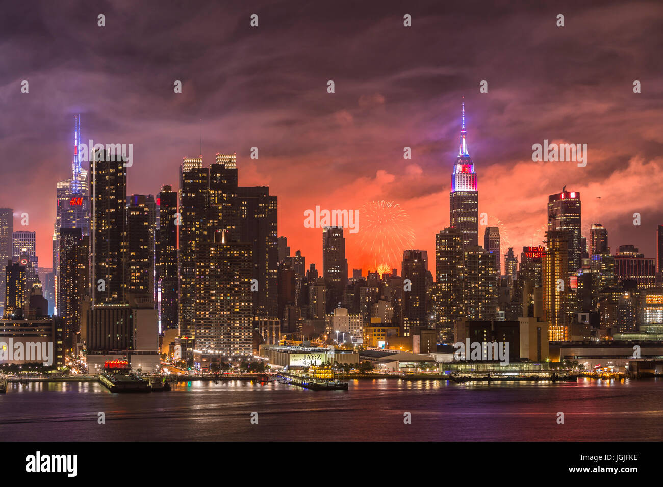 L annuale Macy's quarta di luglio mostra fuochi d'artificio illumina il cielo dietro la skyline di Manhattan a New York City come viste attraverso il fiume Hudson. Foto Stock