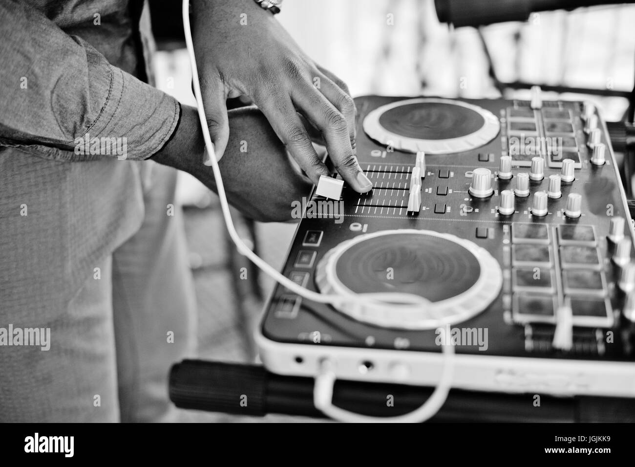 African American dj in enormi cuffie bianche creazione di musica su pannello di miscelazione. Foto in bianco e nero. Foto Stock