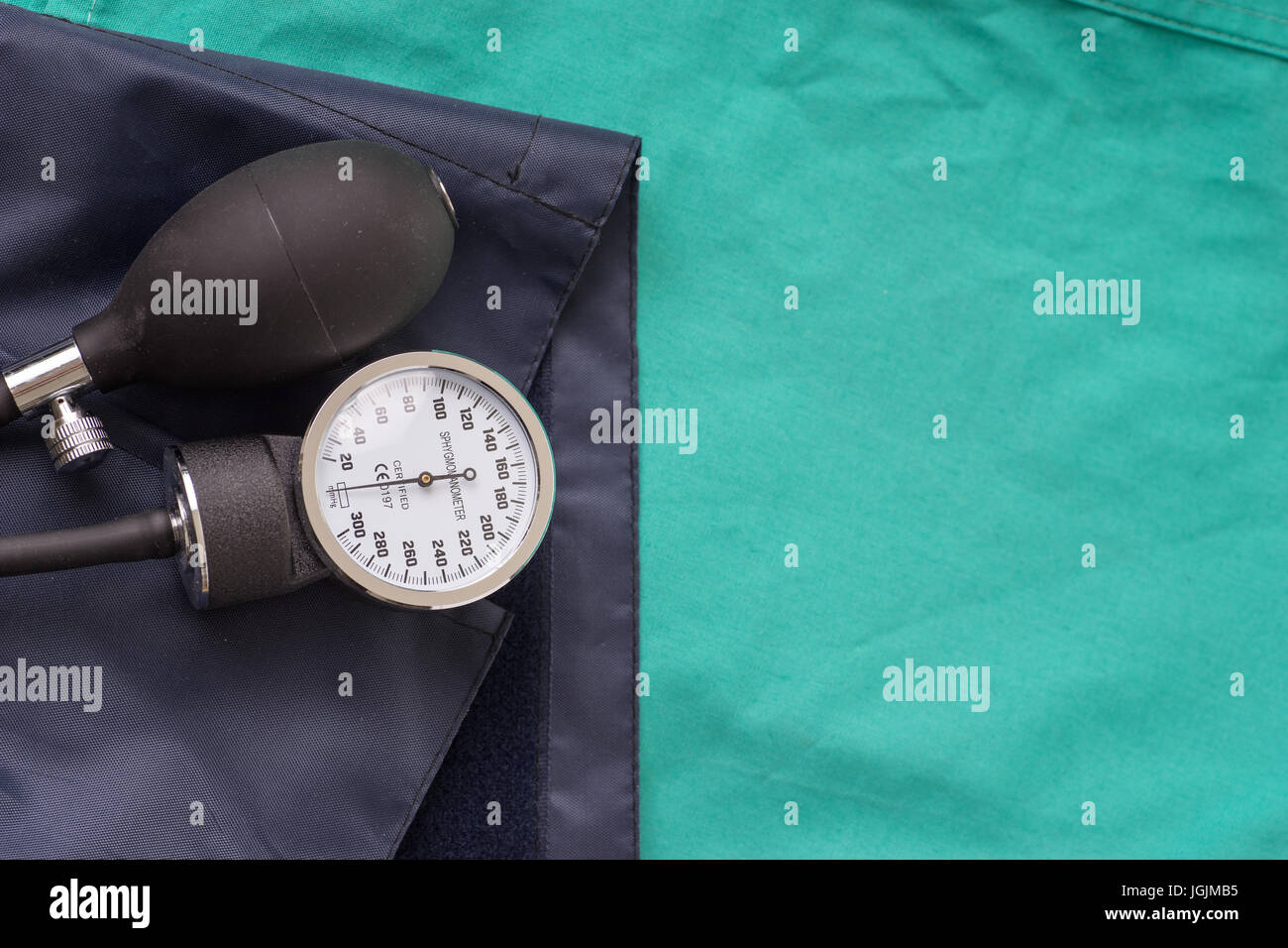 La pressione sanguigna dispositivo situato sull'ospedale sfondo verde. Lo sfondo può essere una parte di tessili di un medico o un infermiere uniforme di lavoro Foto Stock