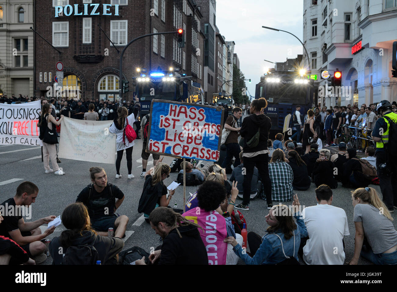 Amburgo, Germania. 07 Luglio, 2017. Germania, Amburgo, protesta rally sul Reeperbahn in St. Pauli contro summit G-20 nel luglio 2017, manifestante seduto di fronte a forze di polizia cannone ad acqua/DEUTSCHLAND, Hamburg St. Pauli, dimostrazione di protesta auf der Reeperbahn gegen G20 Gipfel in Amburgo, vor Sitzblockade Wasserwerfern an der Polizeistation Davidwache Credito: Joerg Boethling/Alamy Live News Foto Stock