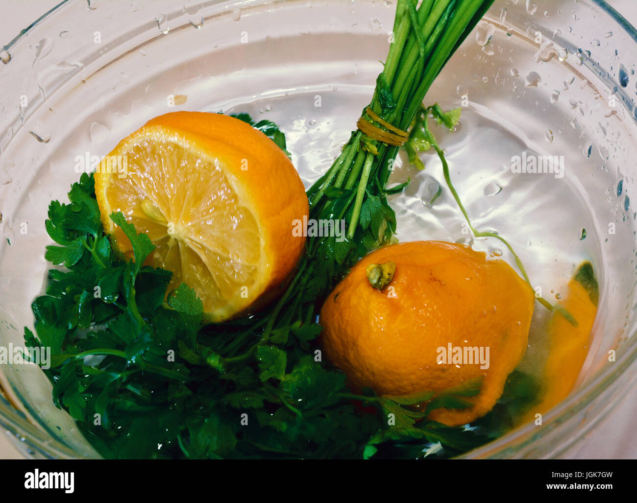 Fresco di limone e prezzemolo schizzi in una ciotola con acqua Foto Stock