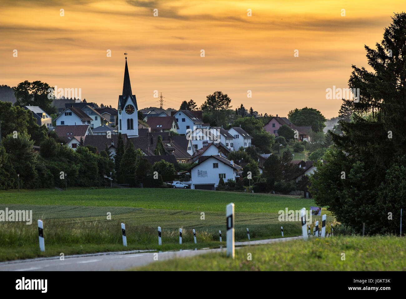 Sole che tramonta dietro il tradizionale villaggio svizzero Foto Stock