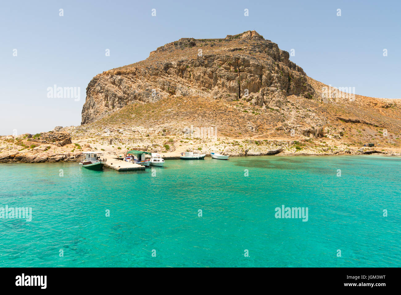 Il piccolo molo per visitatore gite in barca sulla remota isola di Gramvoussa, a nord-ovest di Creta, Grecia. Una rovina del castello si trova sulla cima della collina. Foto Stock