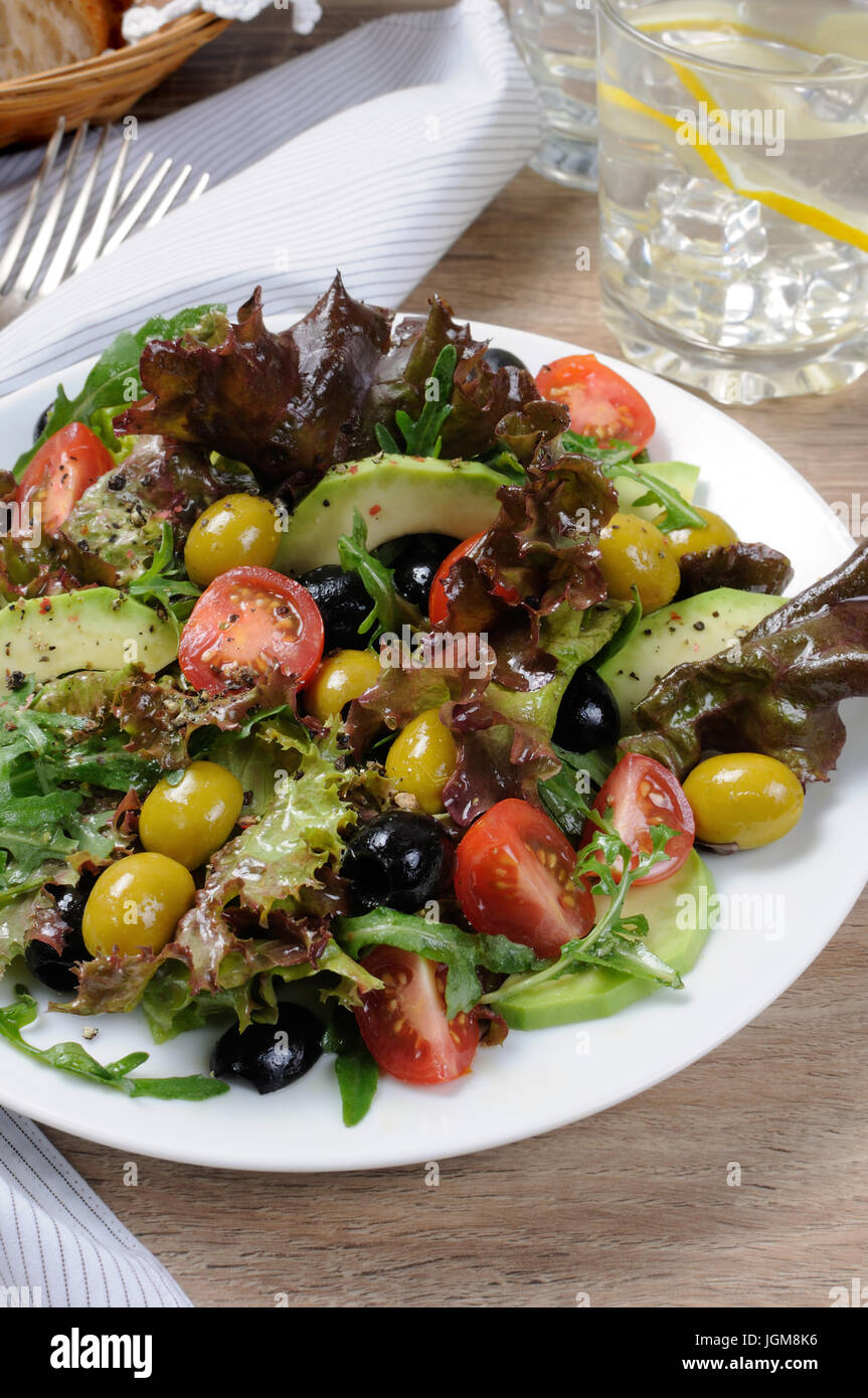 Estate - insalata di avocado, olive, pomodori nella lattuga vestito, senape-salsa di aglio Foto Stock