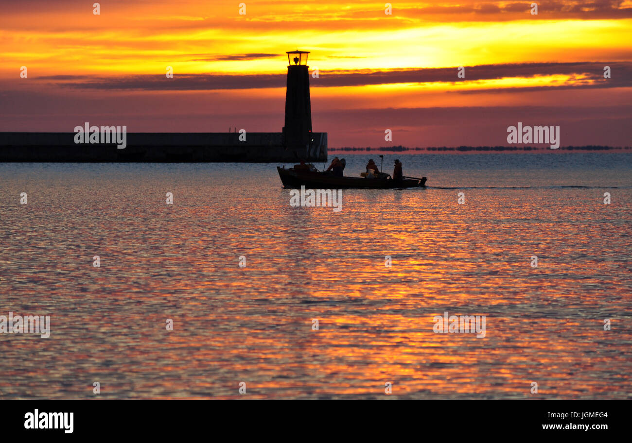 Faro e barche da pesca silhouette luminose durante l'estate l'alba sul mar baltico a Gdynia, Polonia Foto Stock