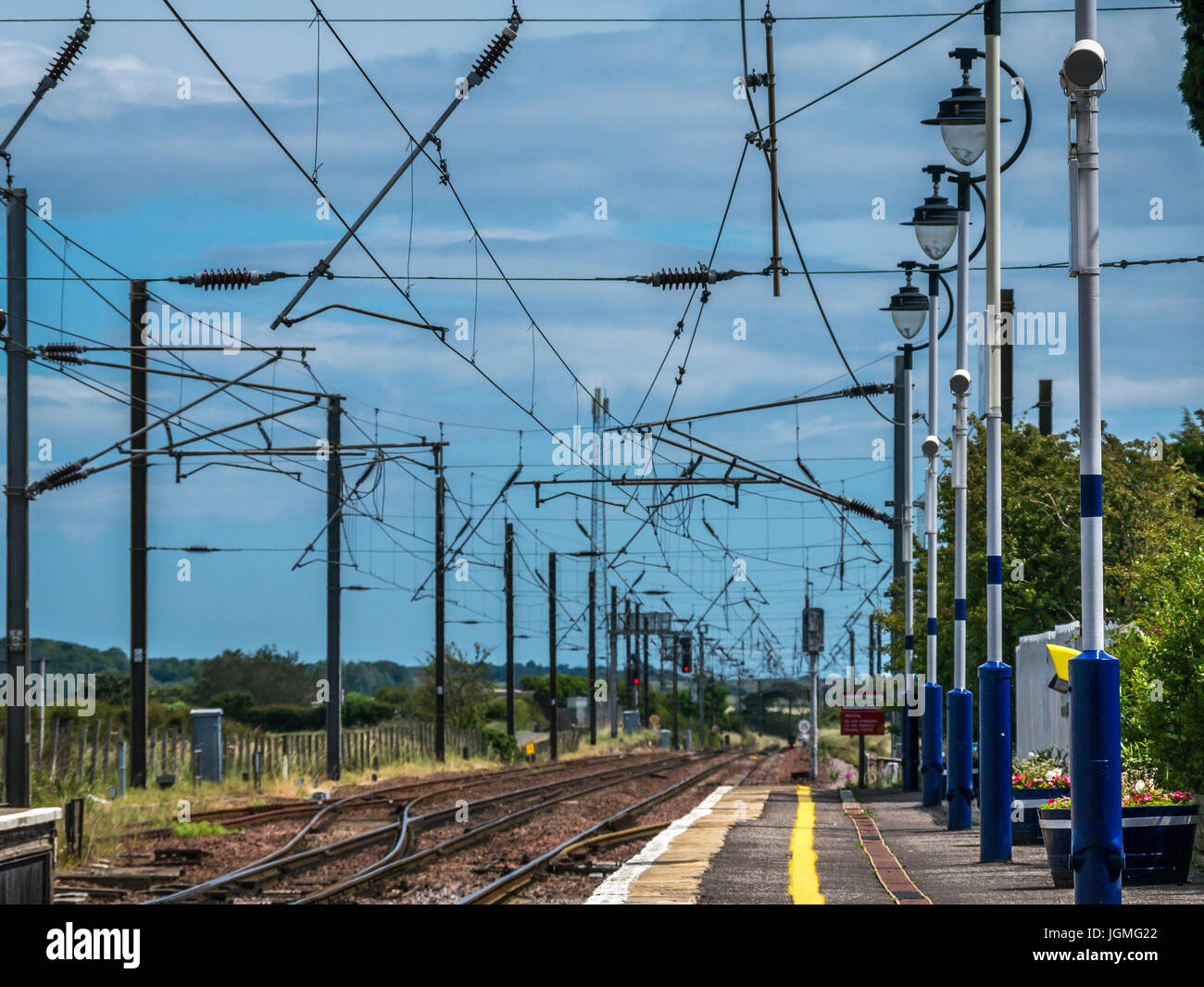 Treno Drem staton piattaforma e visualizza in basso di binari ferroviari con cavi aerei, East Lothian, Scozia, Regno Unito Foto Stock