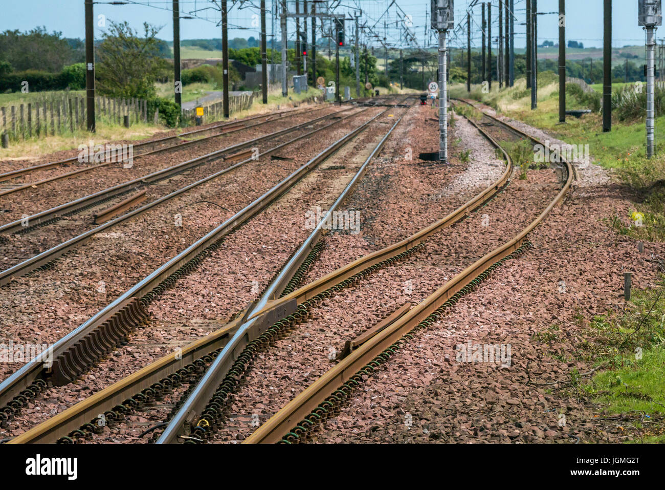 Parallelamente i binari ferroviari con taglio curvo, segnali e cavi aerei, Drem stazione ferroviaria, East Lothian, Scozia, Regno Unito Foto Stock