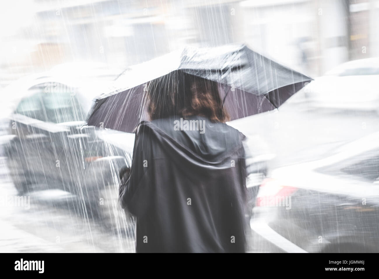 Ragazza con ombrello sulla strada di pioggia - sfocatura del movimento Foto Stock