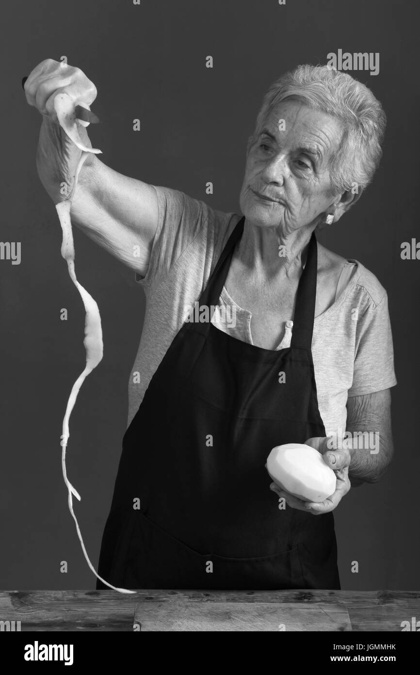 Senior donna pelare patate Foto Stock
