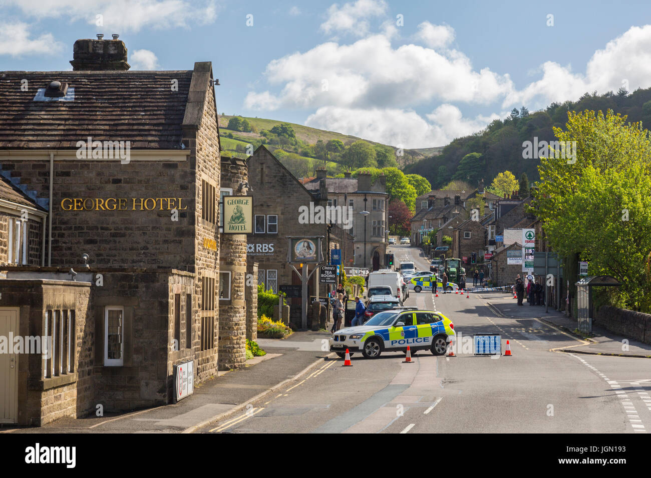 La polizia vicino la strada principale che attraversa il villaggio dopo una collisione tra un ciclista e auto a Hathersage, Peak District, Derbyshire, England, Regno Unito Foto Stock
