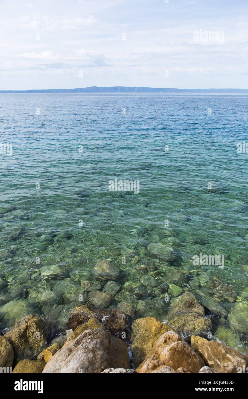 Paesaggio verticale colpo di Mare Adriatico con incredibile acqua chiara.spiaggia rocciosa e il profondo blu del colore dell'acqua.Nuvoloso blu e grandioso luogo naturale.Seasid Foto Stock