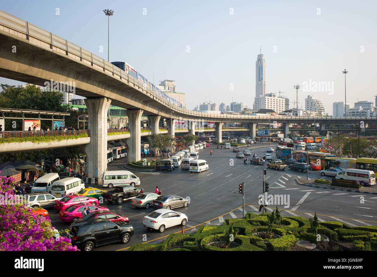 Il traffico su strade di accesso alla rotonda al Monumento della Vittoria, con passaggio pedonale e BTS Skytrain sul viadotto overhead. Bangkok, Thailandia Foto Stock