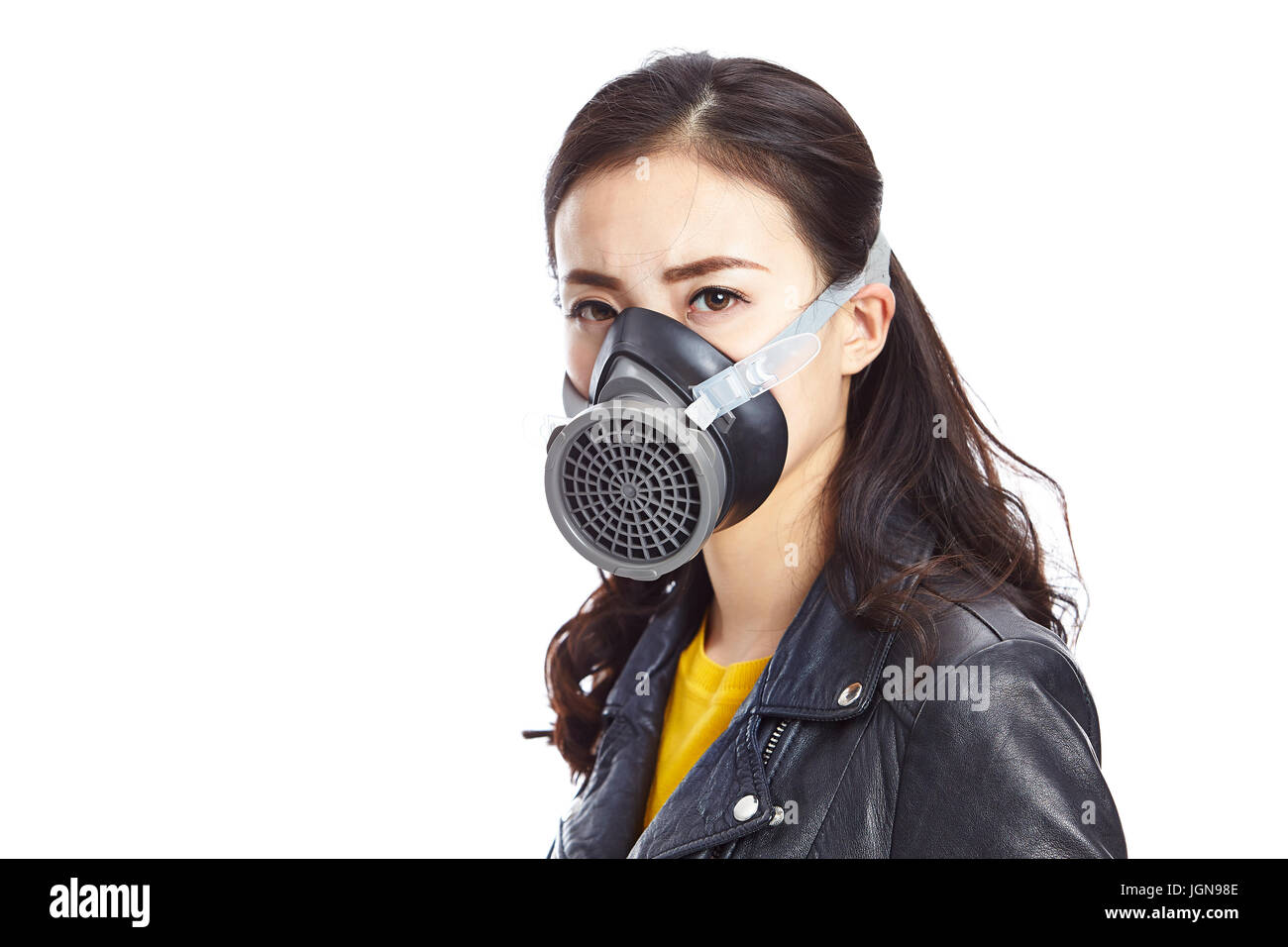 Giovane donna asiatica in pelle nera indossando maschera a gas fissando fotocamera, isolati su sfondo bianco. Foto Stock