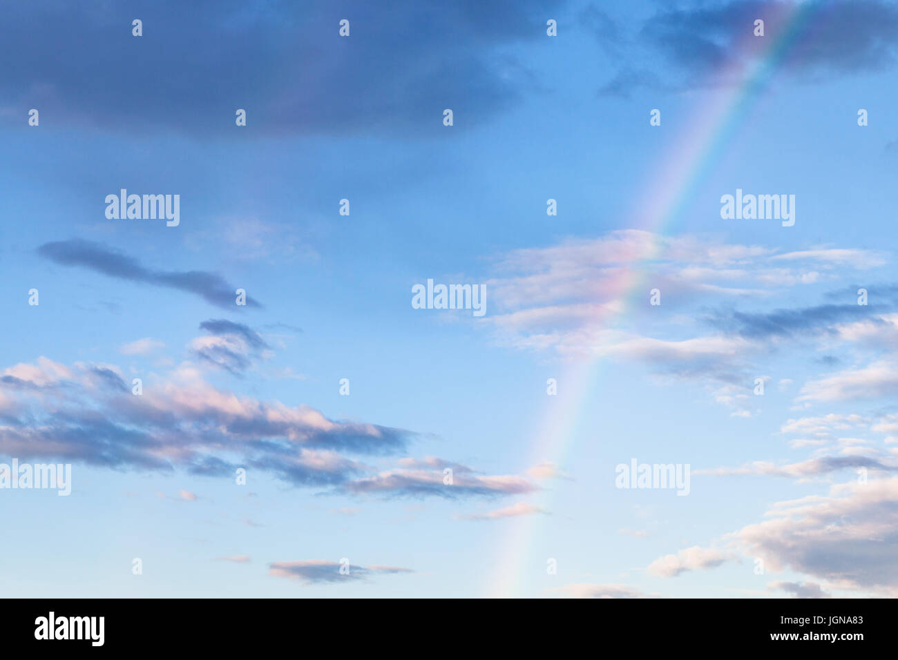 Arcobaleno e nuvole grigie nel blu del cielo della sera in estate Foto Stock