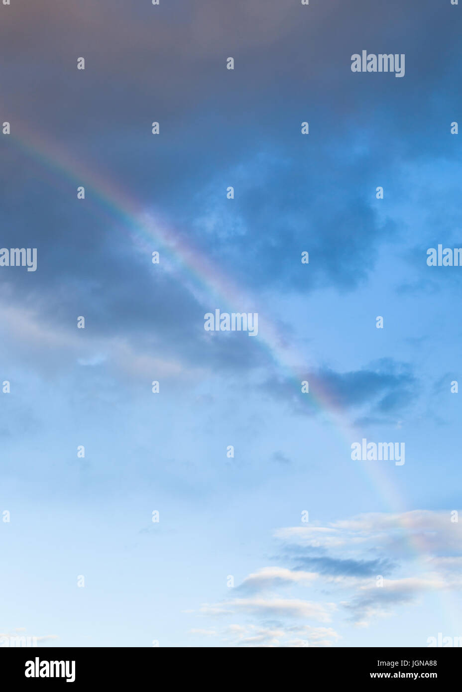Rainbow tra le nuvole scure nel blu del cielo della sera in estate Foto Stock