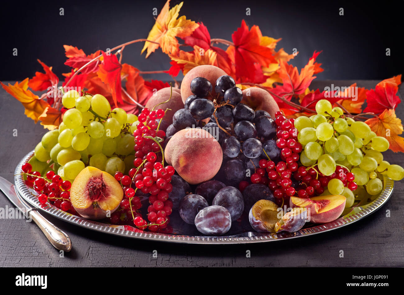 Frutti in autunno in un vassoio su sfondo scuro Foto Stock