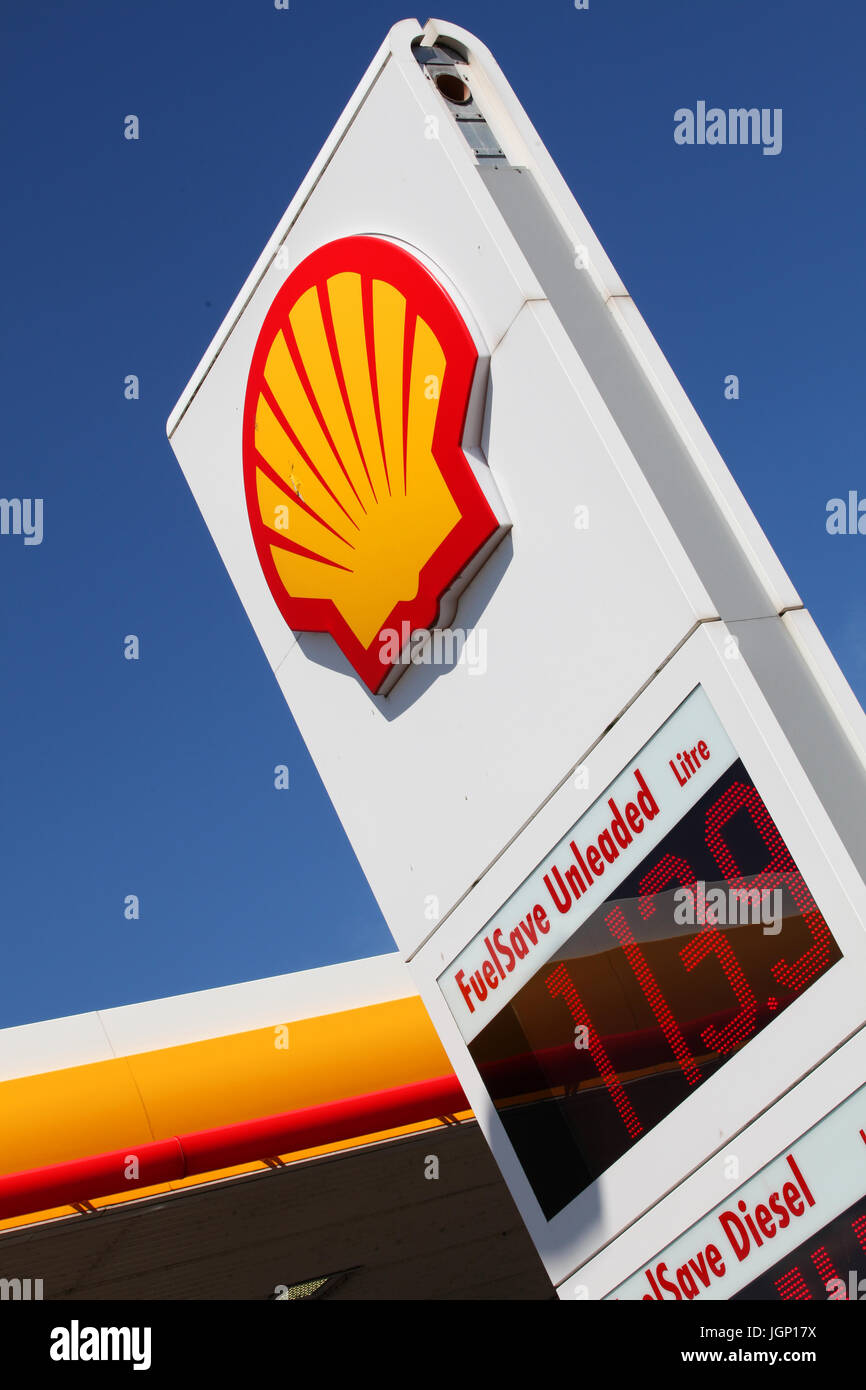 Un distributore di benzina Shell evidenziato il logo contro un luminoso cielo blu Foto Stock