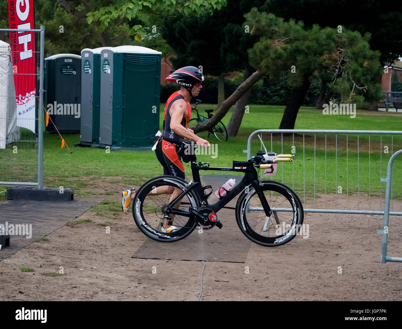 Un triatleta corre con la sua bicicletta durante la fase di transizione di un triathlon Foto Stock