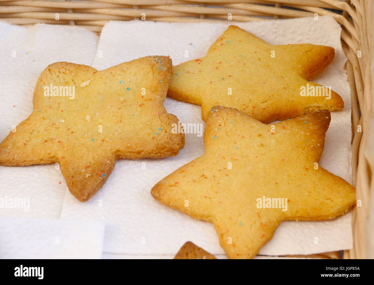 Tre stelle di zucchero a forma di cookie con spruzzi di arcobaleno in un cesto di vimini Foto Stock