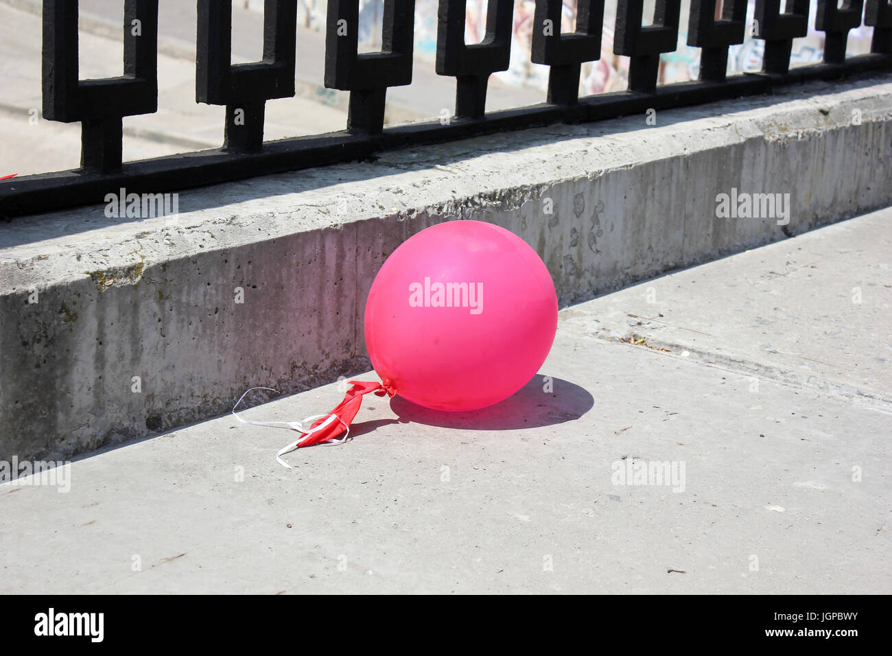 Palla rosa sul terrapieno di cemento con una recinzione metallica Foto Stock