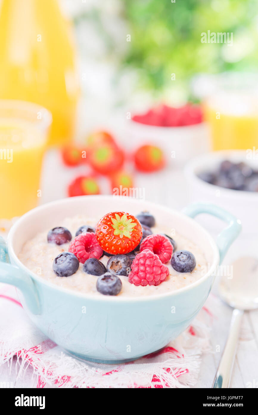 Una ciotola con fatti in casa i fiocchi d'avena porridge con frutta fresca su un rustico tavolo esterno. Foto Stock