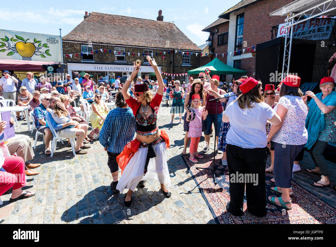 Il gruppo di musica, il favoloso Fezheads eseguendo un concerto presso il Folk e Ale evento a Sandwich Kent. I membri del pubblico e la banda compresa la loro danza del ventre, ballare di fronte al palco nella piazza del paese. Foto Stock