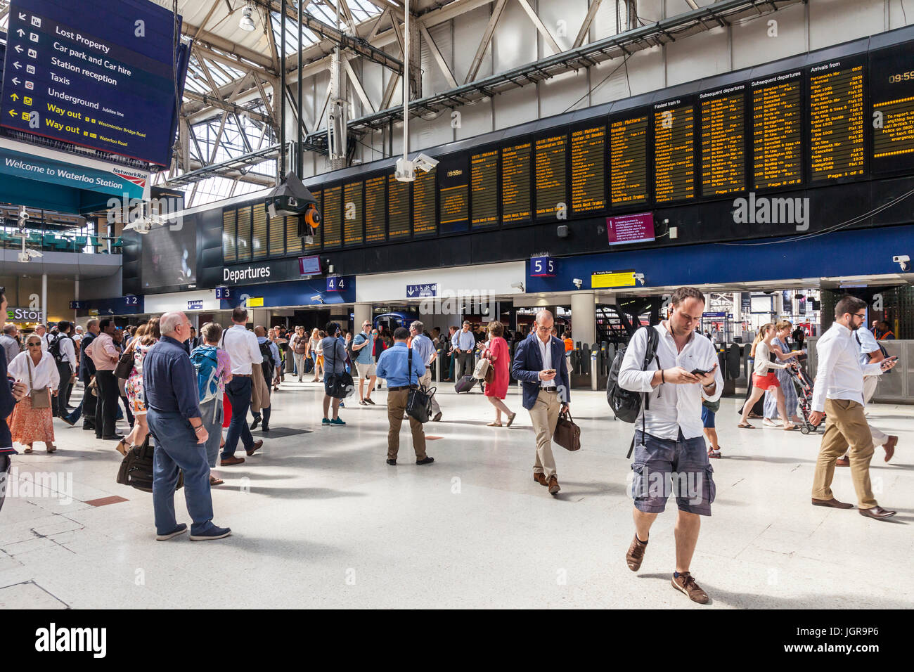 Passeggeri, piazzale di arrivi e partenze e scheda segnaletica direzionale in stazione di Waterloo, una grande stazione terminale a Lambeth, Londra centrale. Foto Stock