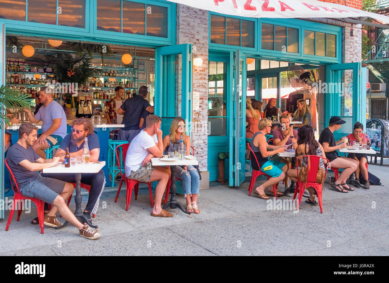 Giovani hipsters a tavoli esterni al Pizza Beach su Orchard Street sulla Lower East Side di New York City Foto Stock