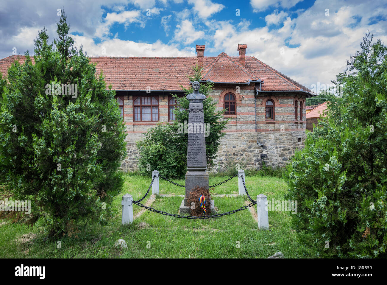 Un monumento di eroi rumeno di fronte generale scuola nel piccolo villaggio di Sibiel famoso dalla tradizionale architettura sassone, Transilvania, Romania Foto Stock