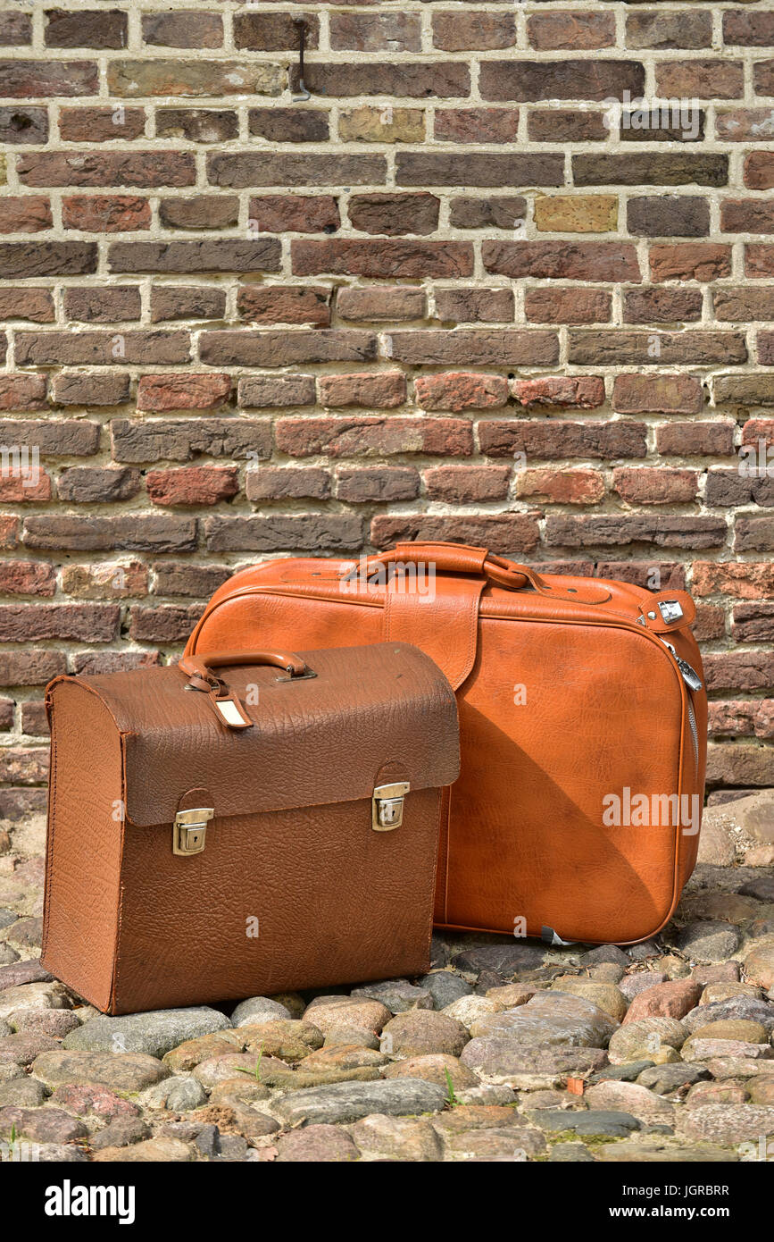 Valigie vintage di un viaggiatore di fronte a un muro di mattoni Foto Stock