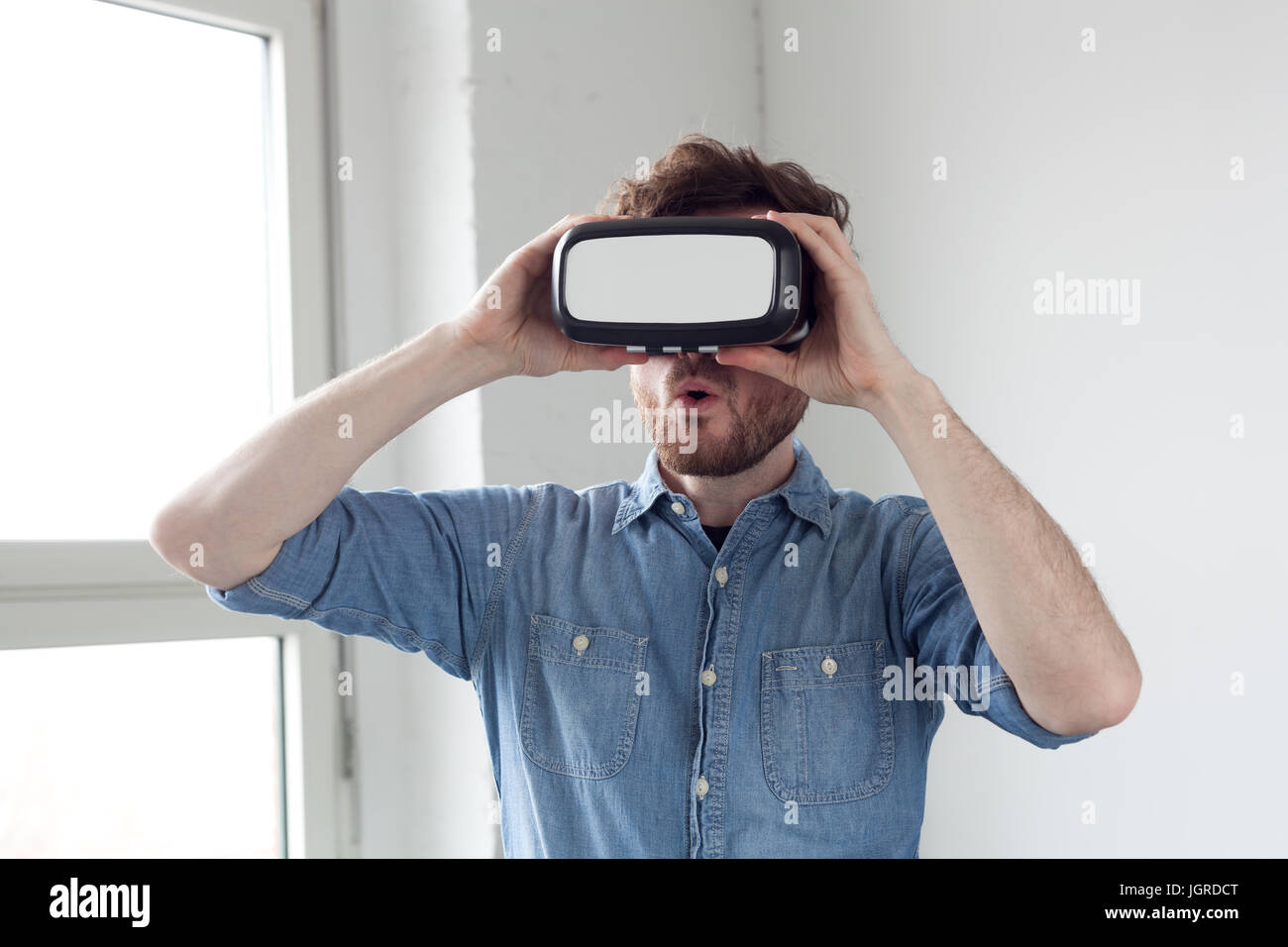Stupito uomo che indossa la realtà virtuale gli occhiali di protezione Foto Stock