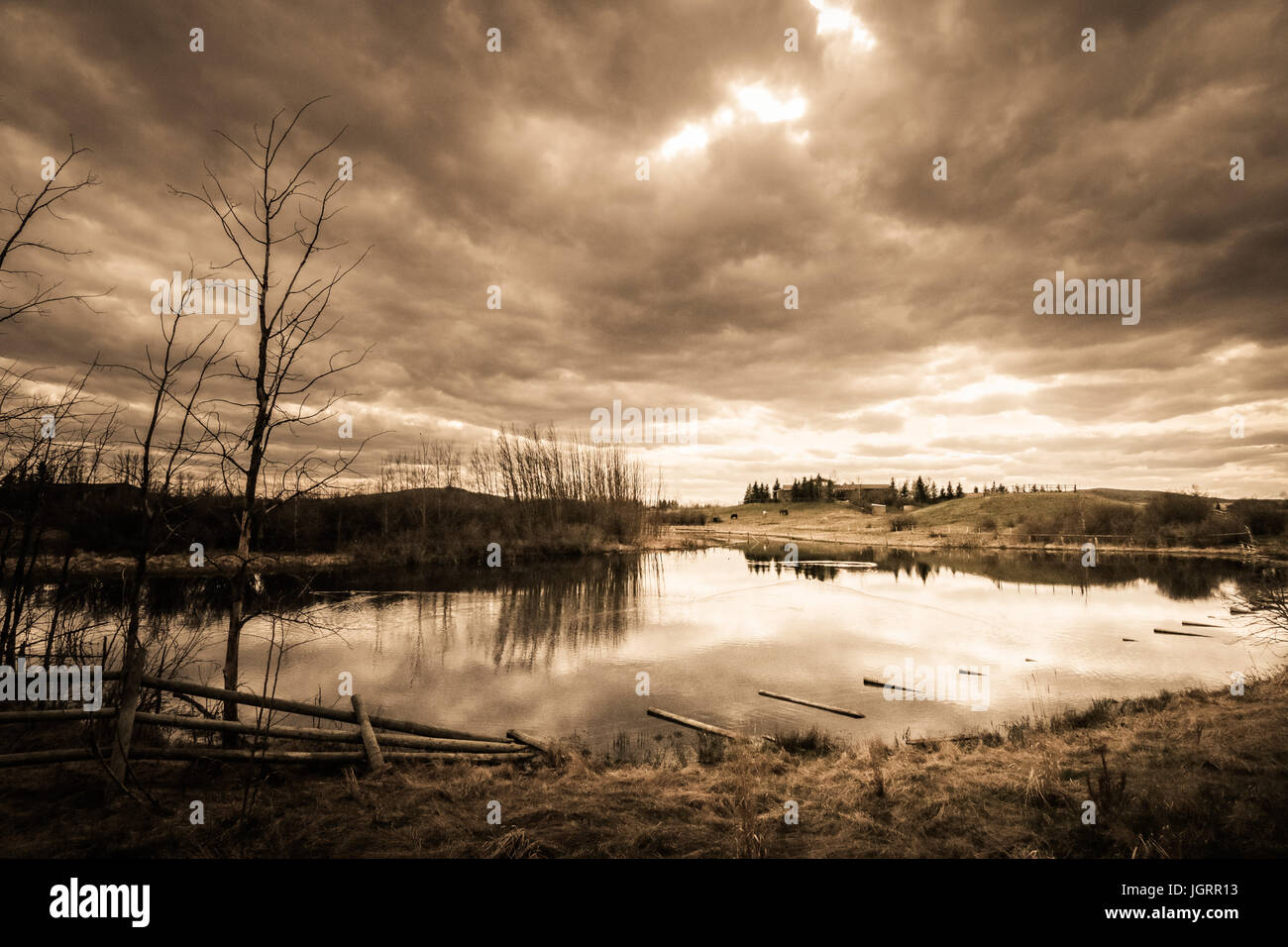 Le nuvole capovolto su un cielo rabbioso riflessa nella ancora acqua di lago. Un drammatico paesaggio minaccia sentimenti di tristezza e di desolazione. Foto Stock