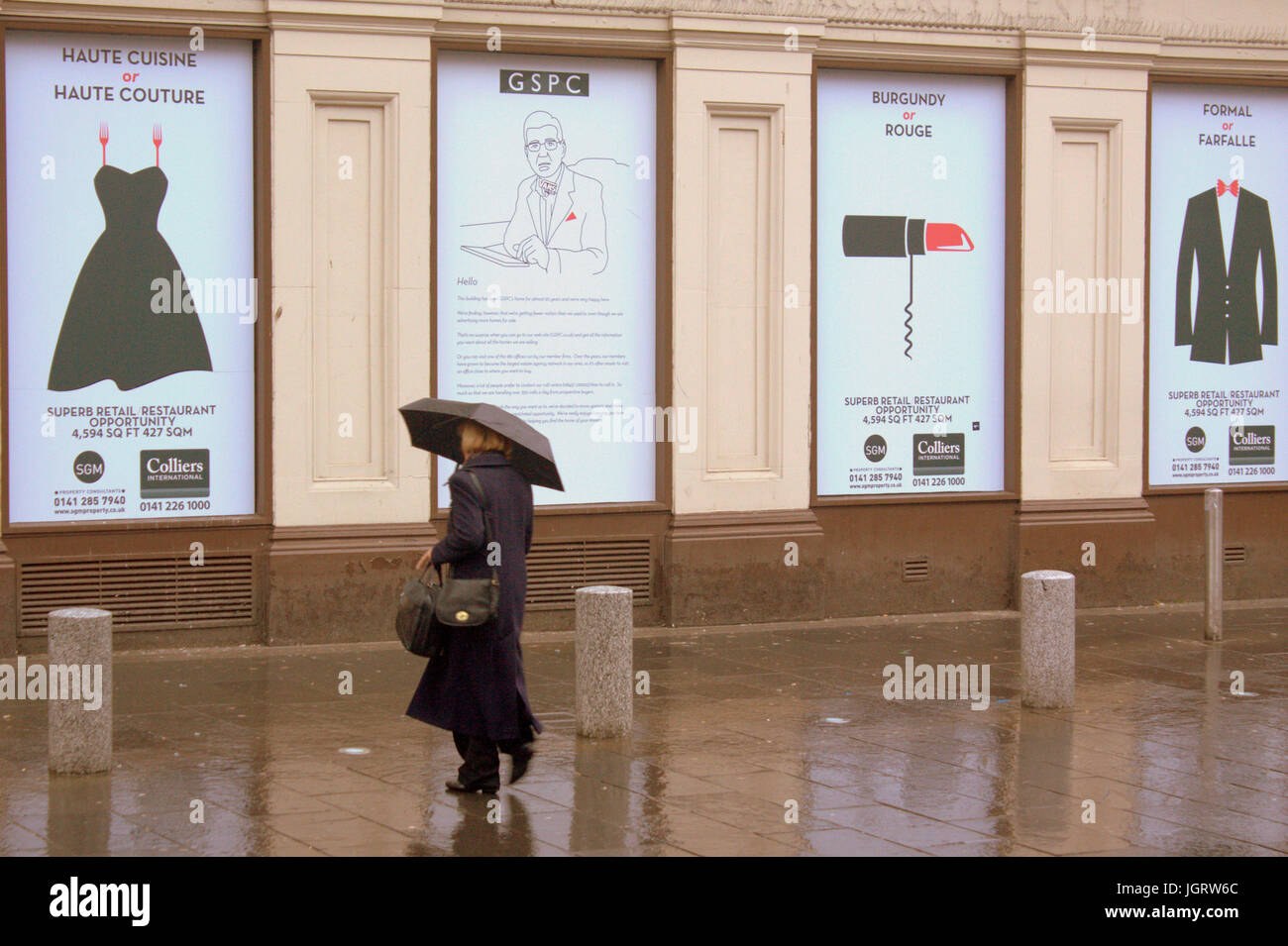 Unico moda donna piove a Glasgow con ombrellone sulla strada bagnata giornata di pioggia brollies cartelloni inserzioni di moda Foto Stock