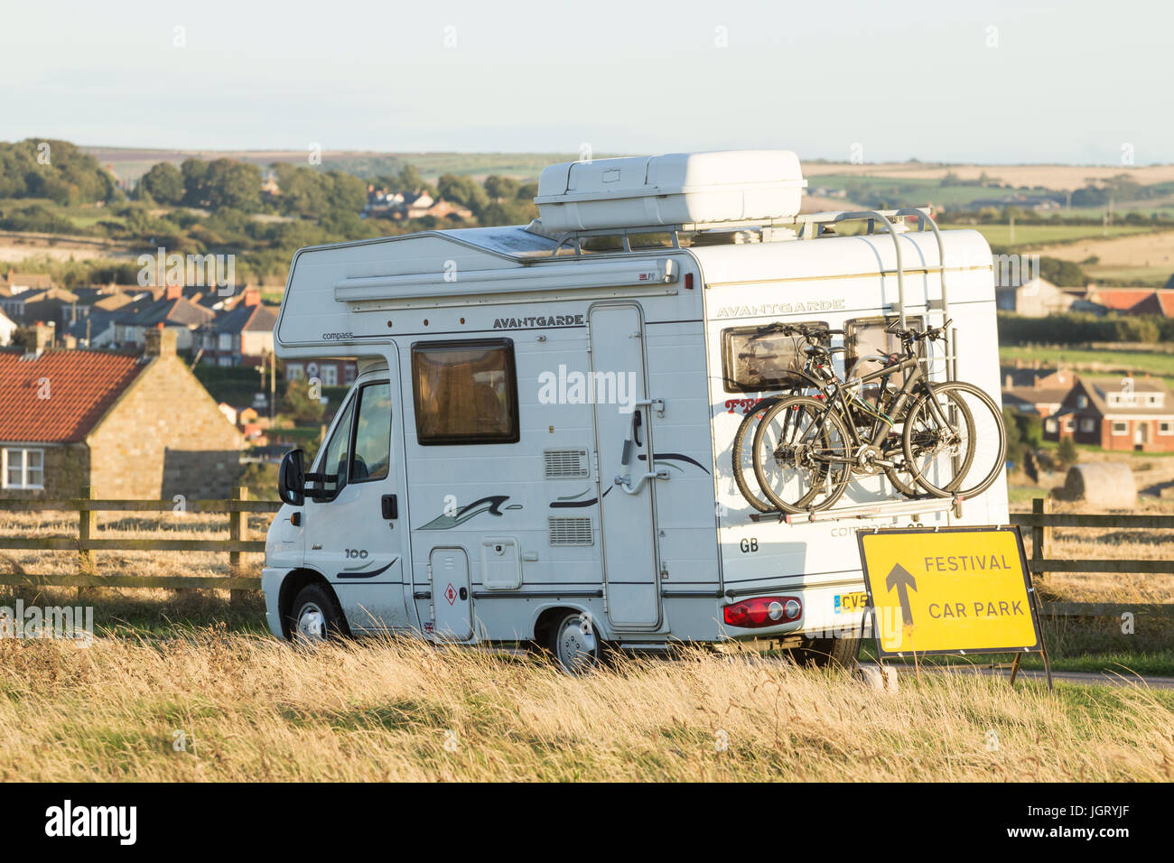 Camper con le biciclette vicino a festival segno parcheggio. Regno Unito Foto Stock