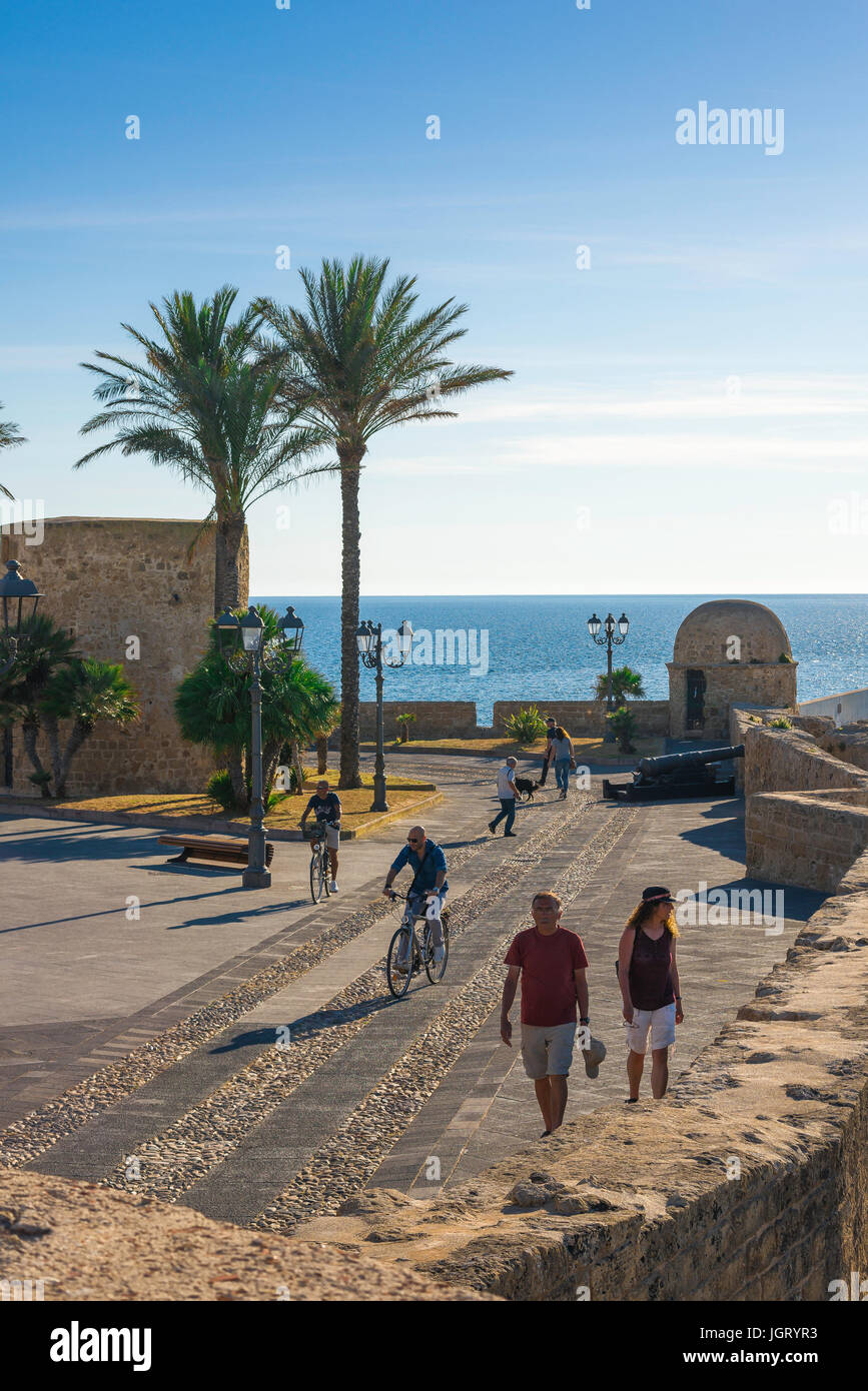 Sardegna Alghero porta, un pomeriggio estivo persone ciclo o passeggiare lungo il mare medievale parete nella zona del porto di Alghero, Sardegna, Italia. Foto Stock