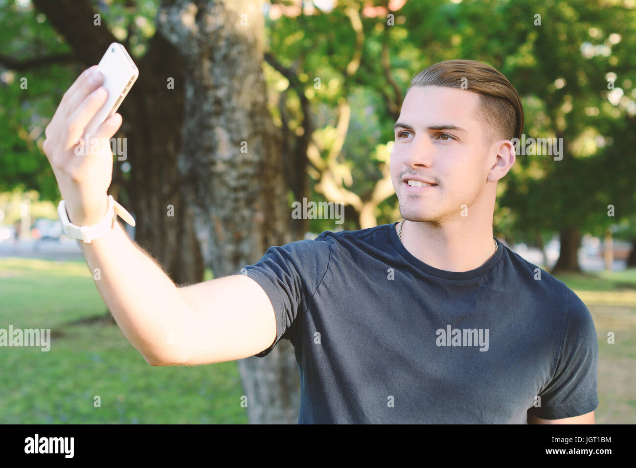 Giovane uomo latino tenendo un selfie con lo smartphone al parco. All'esterno. Foto Stock