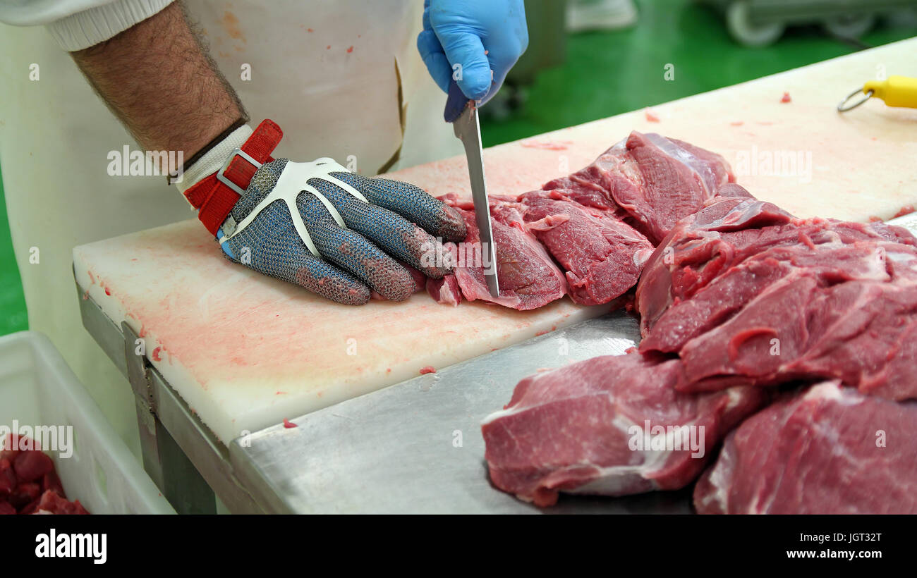 Butcher il taglio di carne di maiale a pezzetti per un mercato di carne. Crudo fresco costolette di maiale nella fabbrica di carne. Trasformazione della carne nel settore alimentare. Foto Stock