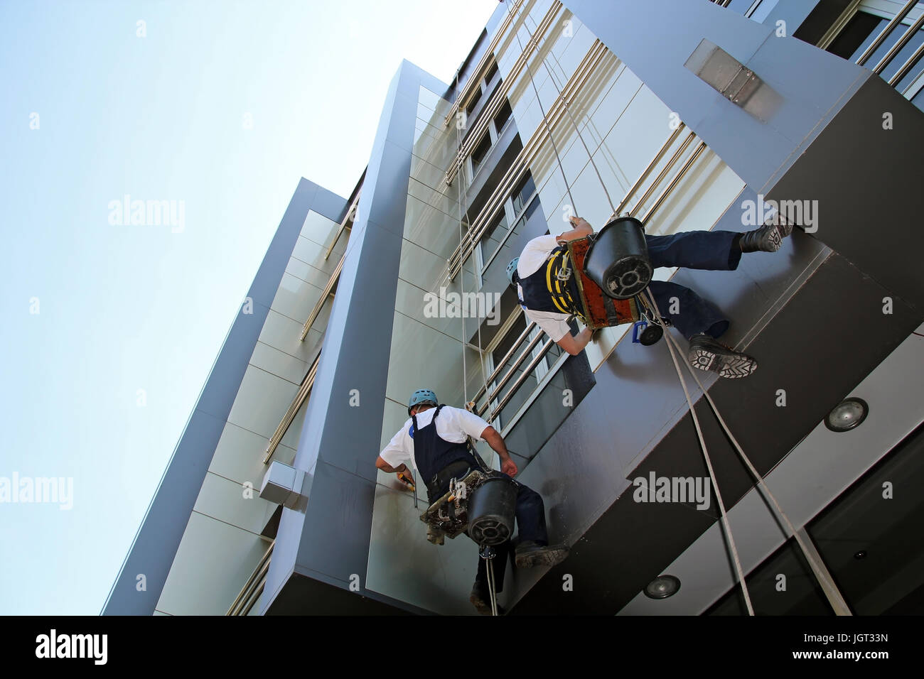 Lavoratori il lavaggio della facciata di Windows di un ufficio moderno edificio. Foto Stock