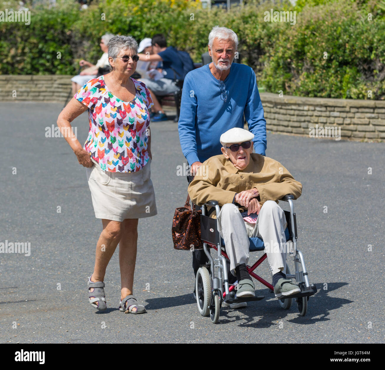 Anziani disabili uomo essendo spinto in una sedia a rotelle. Foto Stock