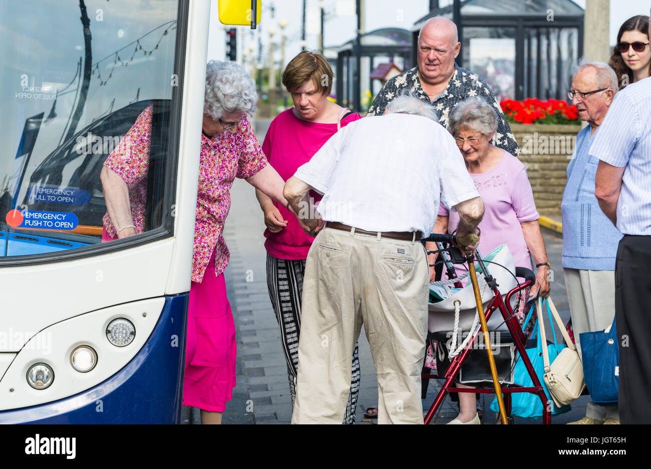 Uomo anziano aiuta una donna anziana scendere un bus. Aiutare gli anziani. Concetto di assistenza. Dare assistenza concetto. Foto Stock