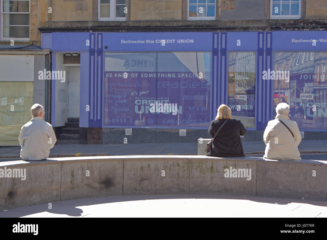 Paisley Scozia buddies su un banco in un posto molto soleggiato giorno, la high street di fronte al locale unione di credito Foto Stock