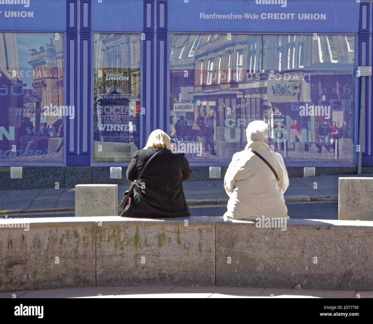 Paisley Scozia buddies su un banco in un posto molto soleggiato giorno, la high street di fronte al locale unione di credito Foto Stock