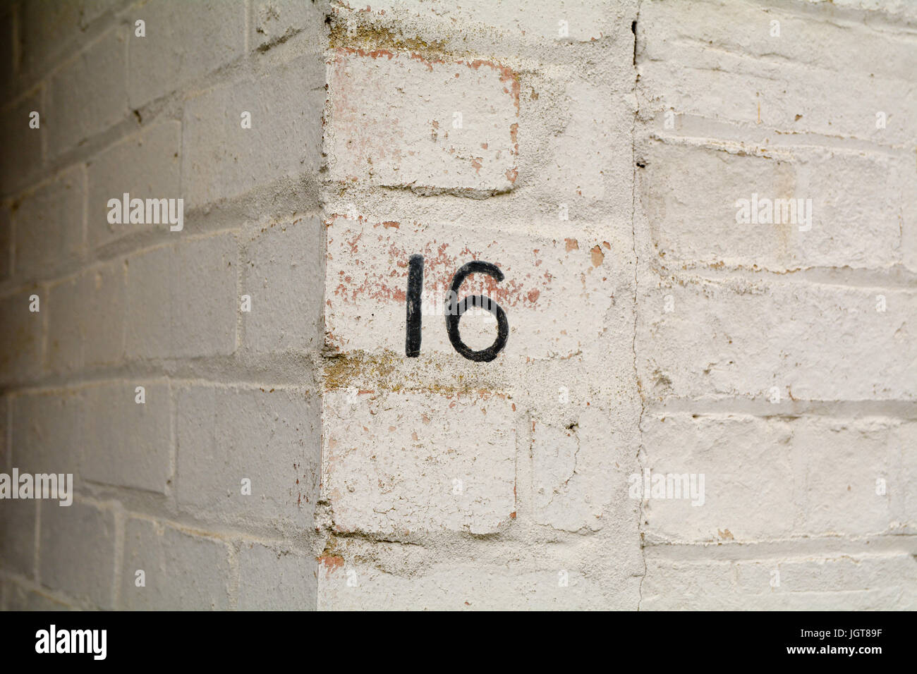 Il numero civico 16 segno dipinto sulla parete Foto Stock Il numero civico 16 segno dipinto sulla parete Foto Stock
