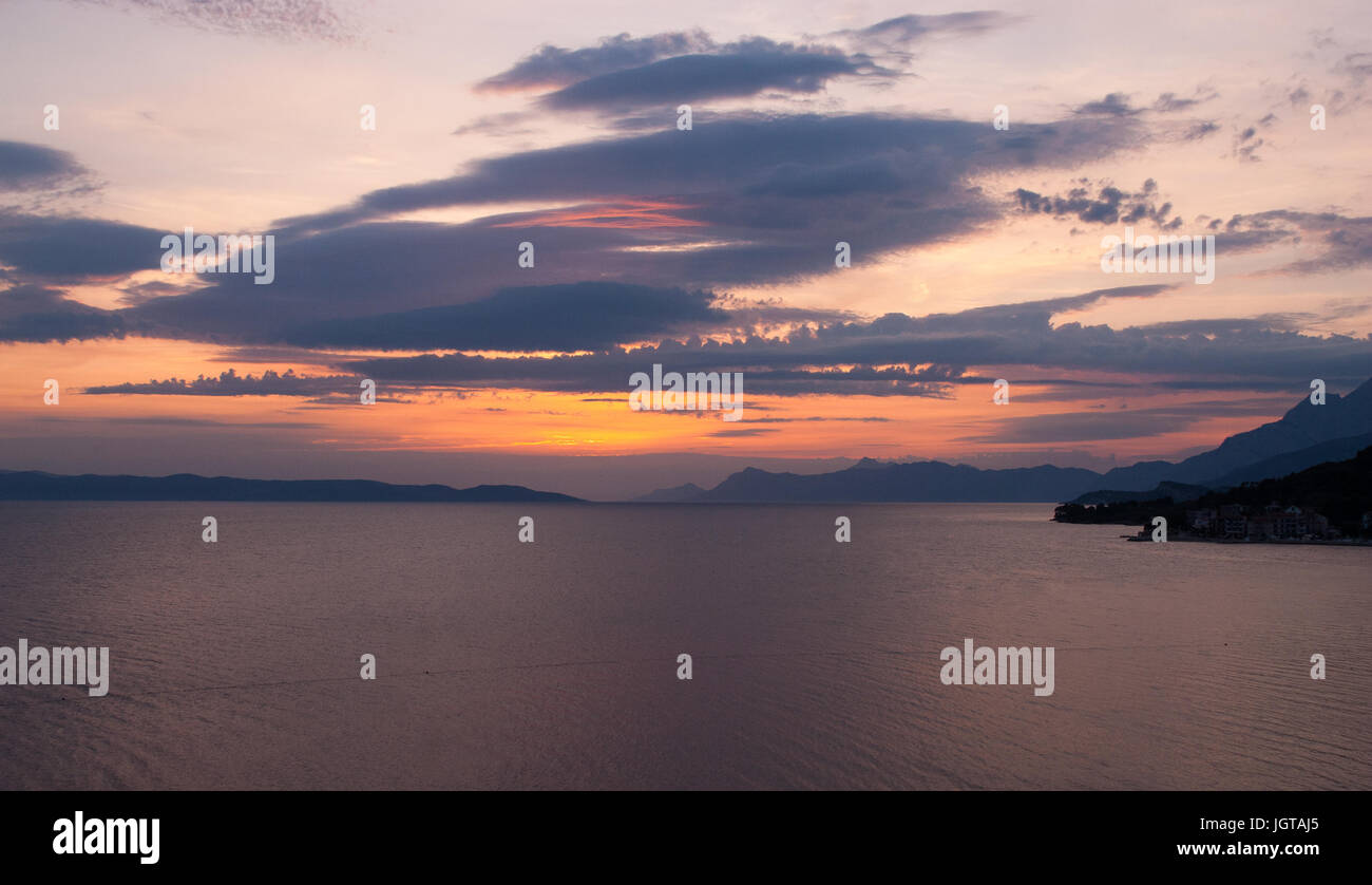 L'immagine orizzontale di profonda tramonto colorato con blu, porpora e sfumature dorate, le montagne nere all'orizzonte, Foto Stock